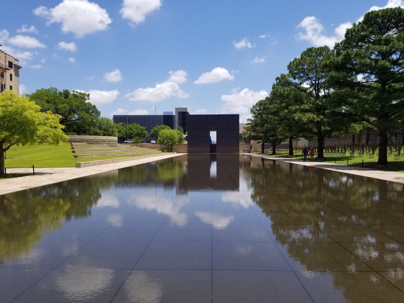 The pool occupies what was once N.W. Fifth Street. Here, a shallow depth of gently flowing water helps soothe wounds, with calming sounds providing a peaceful setting for quiet thoughts. The placid surface creates the reflection of someone changed forever by their visit to the Memorial.